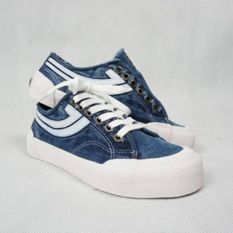 Pair of Denim blue sneakers with white laces on a light gray background