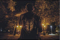 Person wearing a denim jacket with a wolf design standing on a street at night.