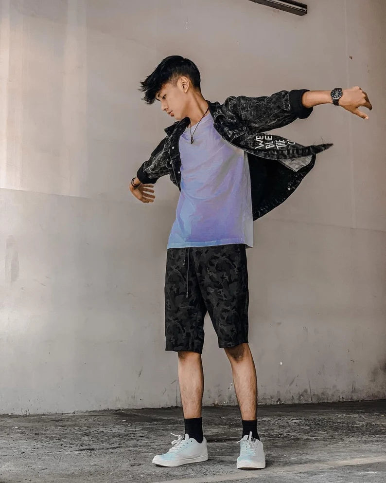 Person wearing a black and white outfit with a gray wall background