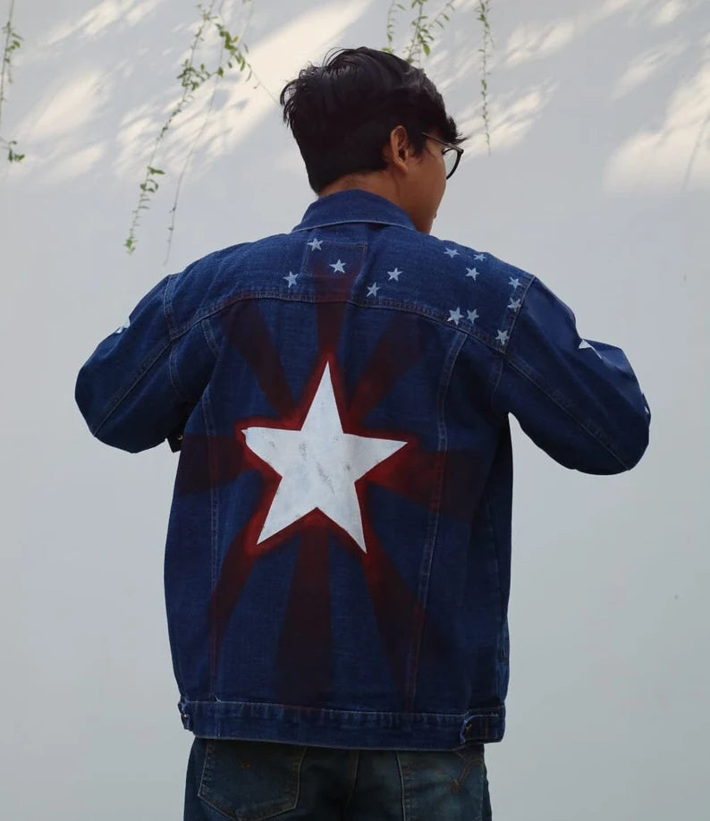 Person wearing a America Chavez Hand-Painted navy blue denim jacket with a large white star on the back, standing against a light-colored wall.