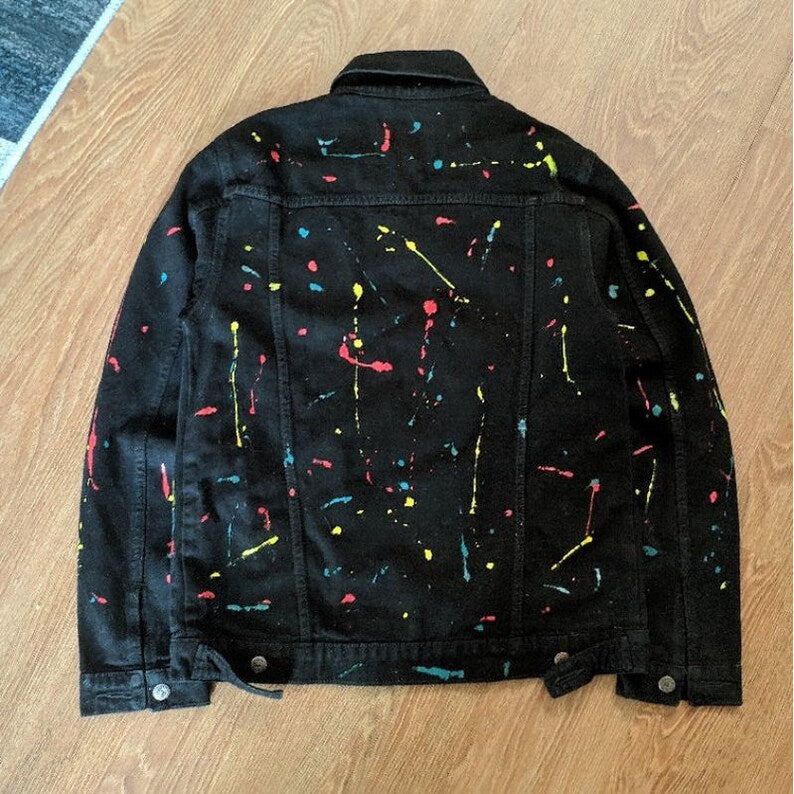 Custom Painted Black jacket with colorful splatter pattern on a wooden floor