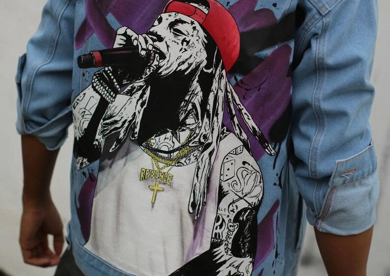 Person wearing a Lil Wayne denim jacket with a graphic design of a person with tattoos and a red cap.