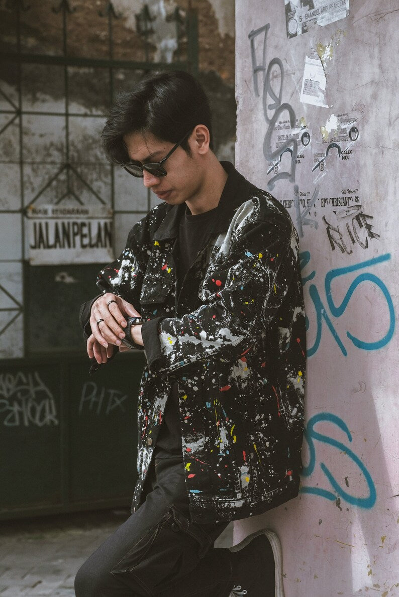 Person wearing a Casual Look Ideas Oversized black jacket with colorful patterns against a graffiti-covered wall.
