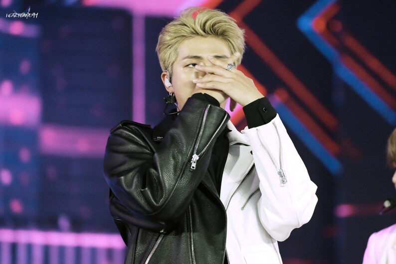 Person with blonde hair covering face with hand on a stage with Monochrome Streetwear Outfits 