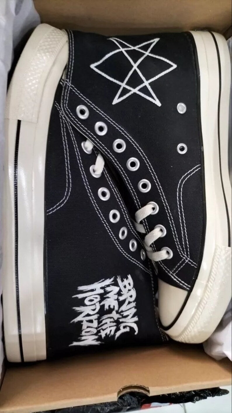 glow in the dark Bring Me The Horizon high-top sneakers with white text and design on a cardboard surface