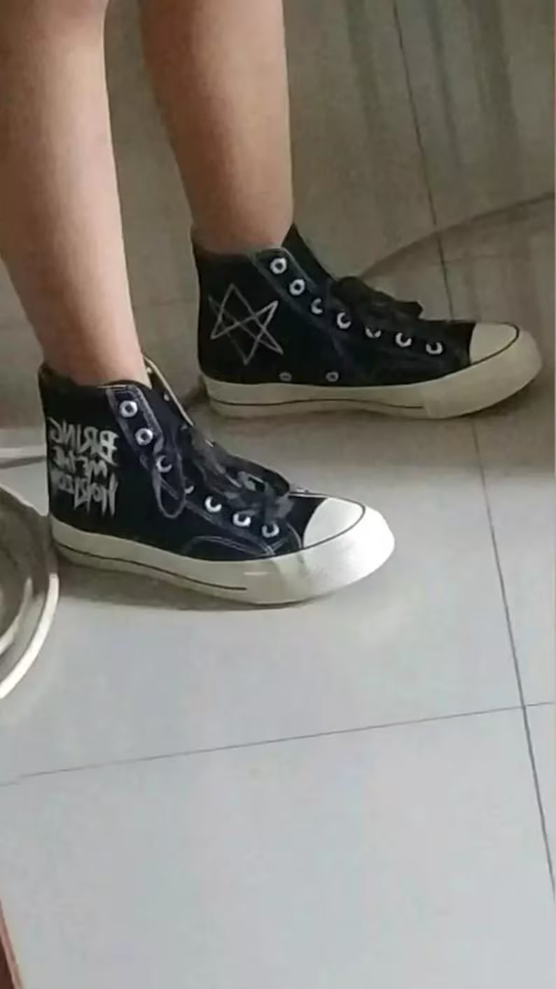 Custom BMTH Merch Black high-top sneakers with white soles on a light-colored floor.