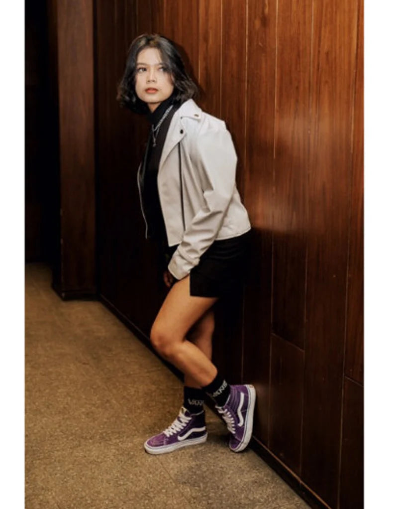 Person leaning against a wooden wall wearing a white jacket and black shorts edgy outfit