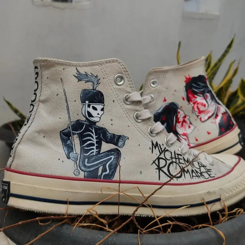 Hand-painted high-top sneakers with My Chemical Romance designs and text, placed on a surface with plants in the background.