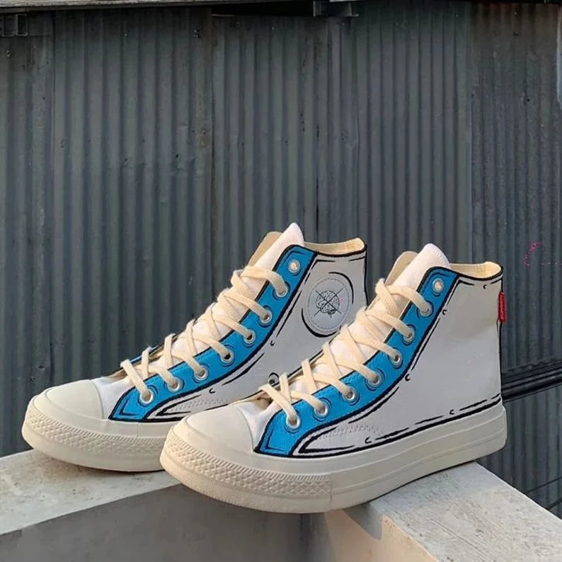 White high-top sneakers with blue accents on a concrete surface against a corrugated metal wall.