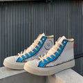 White high-top sneakers with blue accents on a concrete surface against a corrugated metal wall.