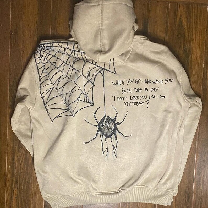 Urban Gothic Punk Beige hoodie with spider and web design on a wooden surface