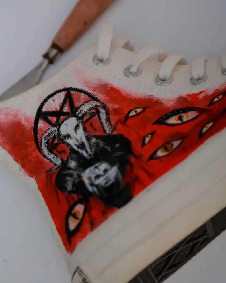 Sabbatic Goat with a black and white illustration of a goat head and pentagram on a red background.