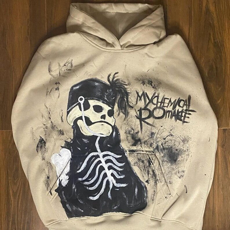 Beige hoodie with a graphic design of a skeleton wearing a mask and 'My Chemical Romance' text on a wooden floor.