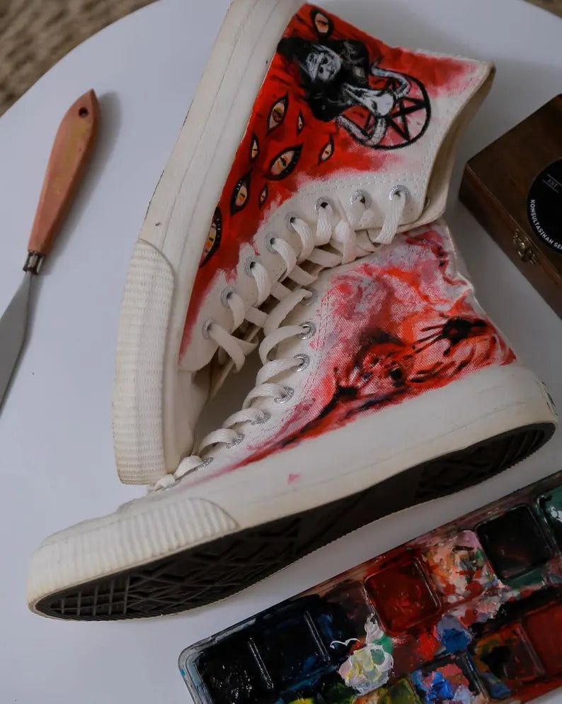 Gothic Halloween Fashion Painted high-top sneakers with artistic design on a white surface with art supplies.