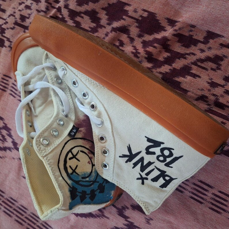 Bespoke Grunge Fashion High-top sneaker with orange heel and white laces on a patterned fabric background