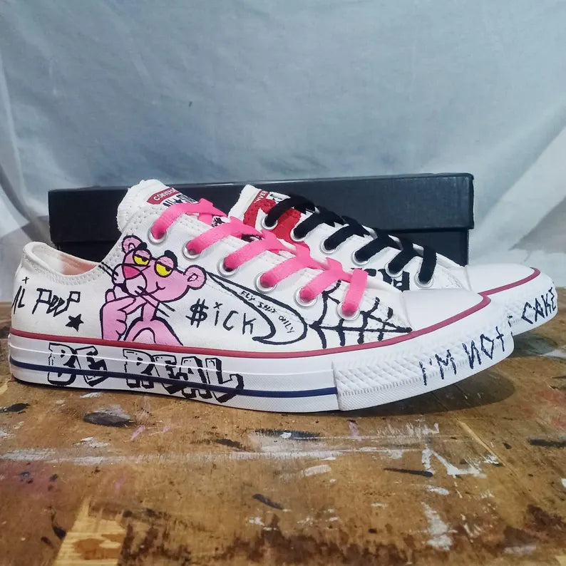 Custom Lil Peep Converse sneakers with pink laces and graphic designs on a wooden surface.