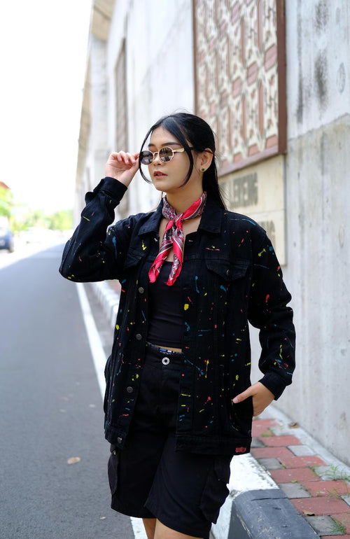 Person wearing a black hand-painted denim jacket with colorful paint splashes and stripes for an artistic street style outfit