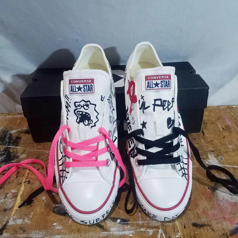 Pair of Punk Rock Shoes for Emo & Streetwear white Converse sneakers with colorful laces on a wooden surface.